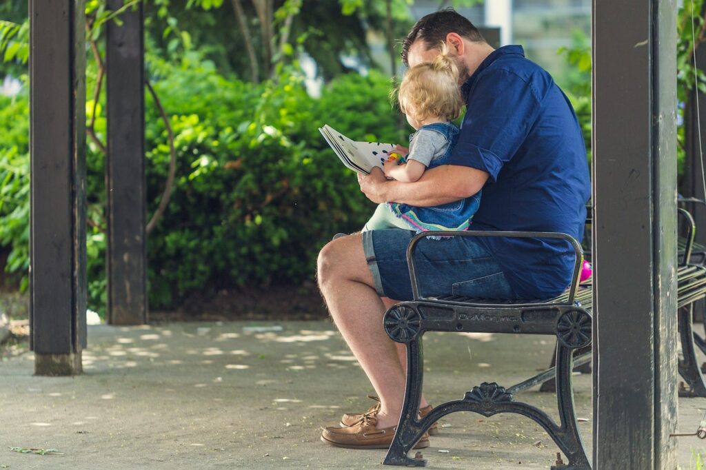 男の子を膝に乗せて絵本を読み聞かせる父親